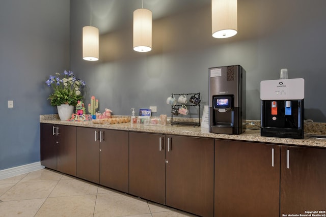 kitchen featuring baseboards, dark brown cabinetry, light tile patterned floors, and light stone countertops