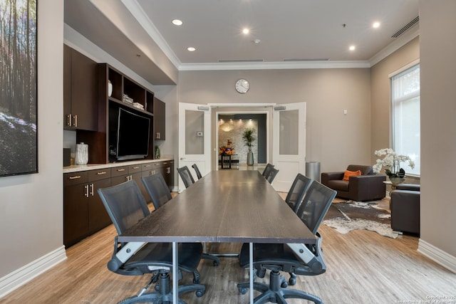 dining room featuring ornamental molding, light wood finished floors, visible vents, and baseboards
