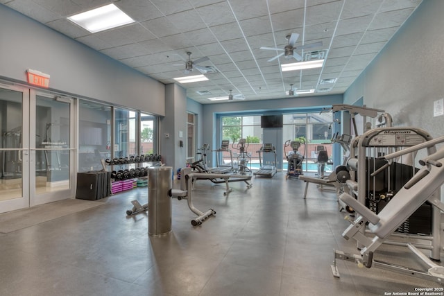 gym with a paneled ceiling, ceiling fan, and french doors