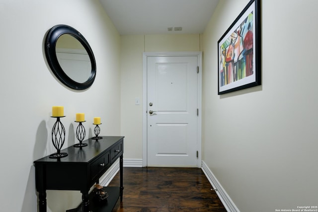 doorway with baseboards and dark wood-style flooring