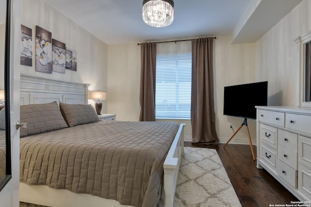 bedroom featuring dark wood-style floors, baseboards, and a chandelier