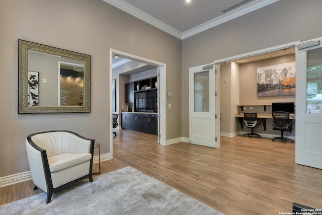 living area with built in desk, crown molding, visible vents, baseboards, and wood finished floors