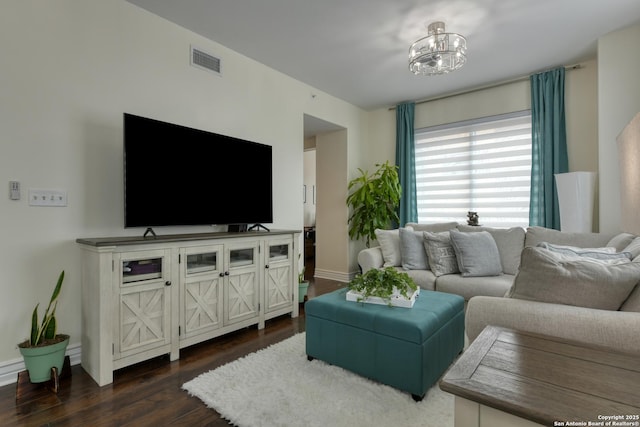living room with baseboards, visible vents, a notable chandelier, and dark wood-type flooring