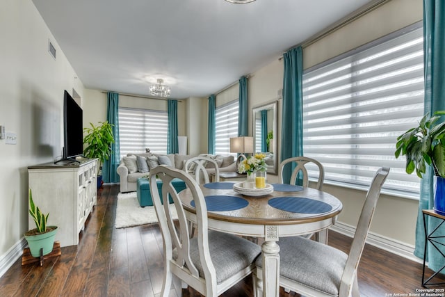 dining room featuring dark wood-style floors, visible vents, a notable chandelier, and baseboards