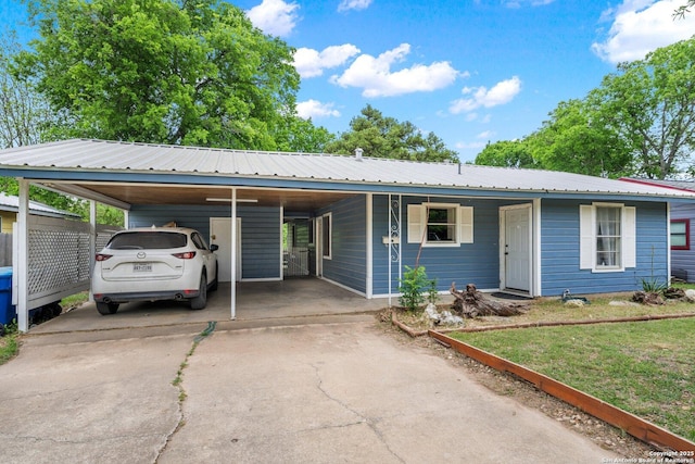 view of front of home featuring driveway, an attached carport, a front yard, and metal roof