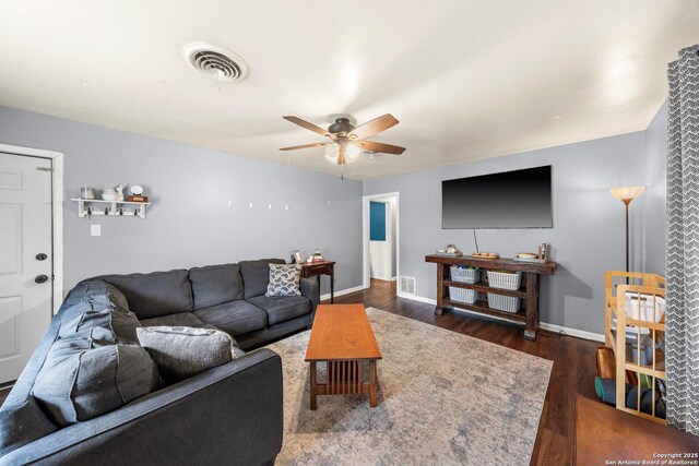 living room featuring baseboards, wood finished floors, visible vents, and ceiling fan