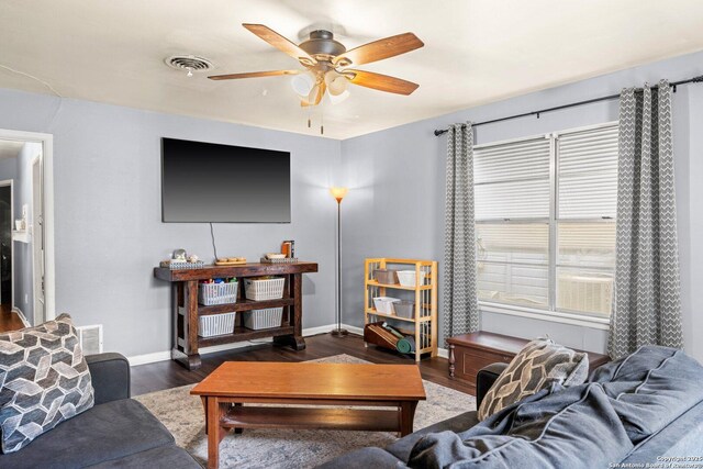 living area featuring visible vents, baseboards, a ceiling fan, and wood finished floors