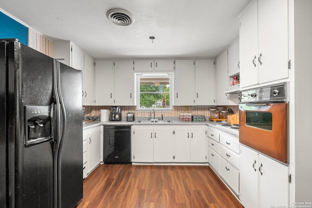 kitchen with a sink, black appliances, visible vents, light countertops, and dark wood-style floors