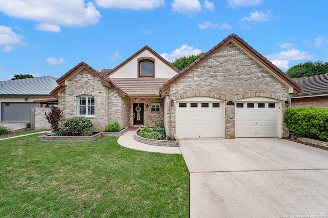 french country inspired facade with a tile roof, a front yard, brick siding, concrete driveway, and an attached garage