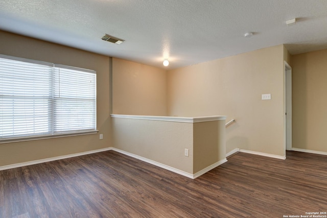 empty room with wood finished floors, baseboards, and a textured ceiling