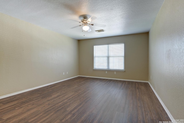 unfurnished room with dark wood finished floors, ceiling fan, baseboards, and a textured ceiling