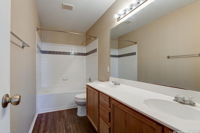 full bath with wood finished floors, toilet, double vanity, and bathtub / shower combination