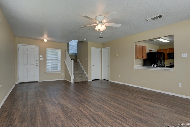 unfurnished living room featuring a textured ceiling, stairway, dark wood-type flooring, ceiling fan, and baseboards