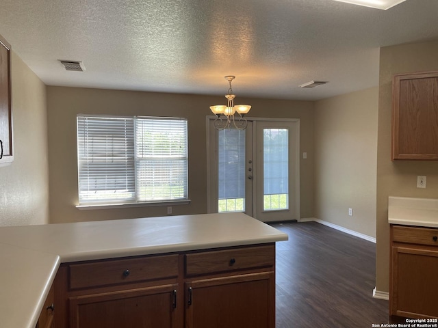 kitchen with dark wood-type flooring, a chandelier, healthy amount of natural light, baseboards, and a textured ceiling