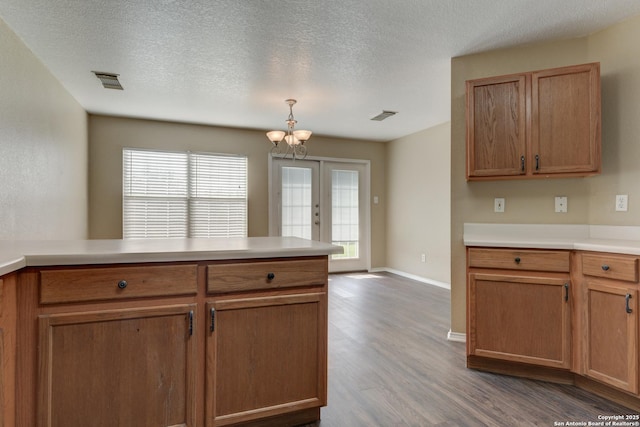 kitchen with dark wood-style flooring, a chandelier, light countertops, baseboards, and a textured ceiling