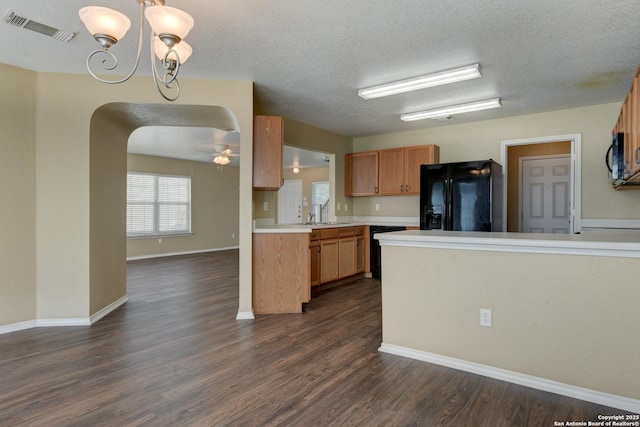 kitchen featuring black appliances, arched walkways, a chandelier, light countertops, and dark wood-style flooring