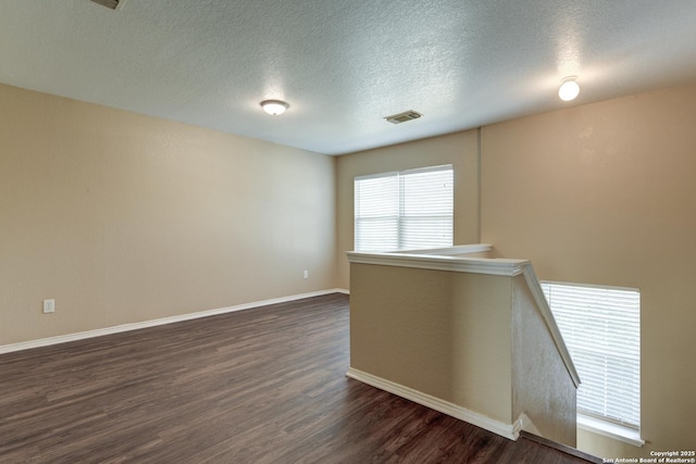 spare room featuring dark wood-style floors, baseboards, and a textured ceiling