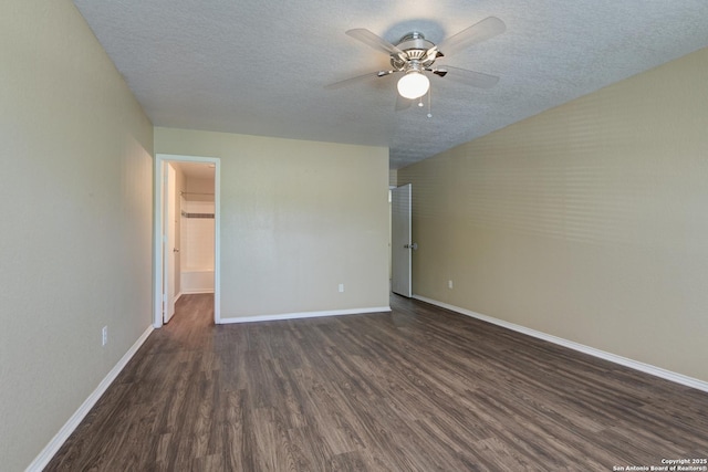 empty room featuring dark wood finished floors, a ceiling fan, a textured ceiling, and baseboards