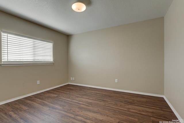 spare room with dark wood-style flooring and baseboards