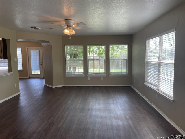 unfurnished room featuring arched walkways, ceiling fan, dark wood-type flooring, baseboards, and a textured ceiling