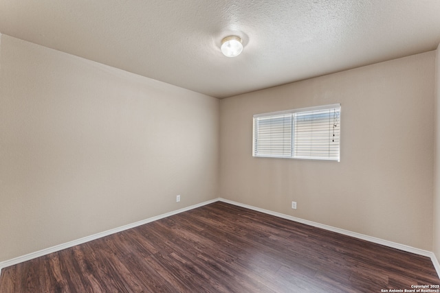 unfurnished room featuring dark wood finished floors, a textured ceiling, and baseboards