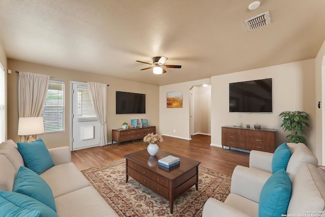living room with ceiling fan, baseboards, wood finished floors, and visible vents