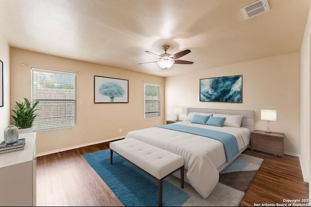 bedroom with baseboards, dark wood-type flooring, multiple windows, and visible vents