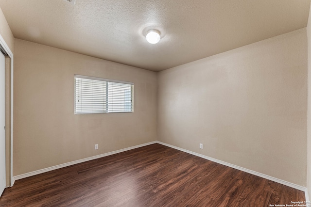 empty room with baseboards, dark wood-style flooring, and a textured ceiling