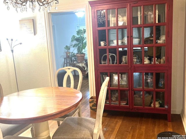 dining space with a textured wall, a notable chandelier, and wood-type flooring