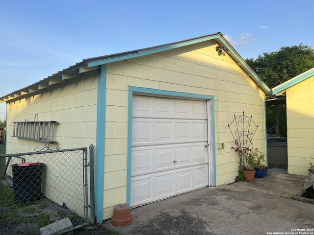 detached garage with central air condition unit, driveway, and fence