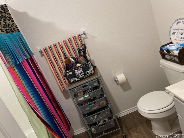 bathroom featuring baseboards, wood finished floors, a shower with shower curtain, and toilet