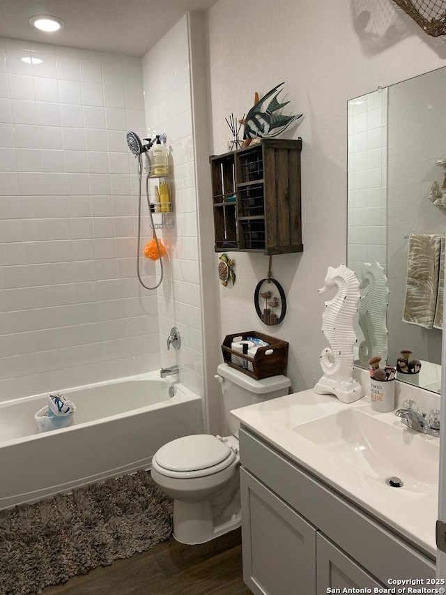 bathroom featuring toilet, vanity, wood finished floors, and shower / tub combination