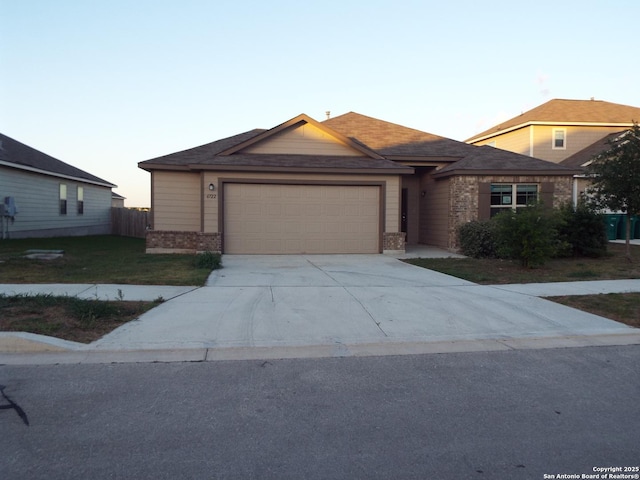 single story home with a lawn, driveway, brick siding, and a garage