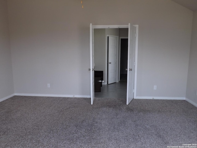 unfurnished room with baseboards and dark carpet