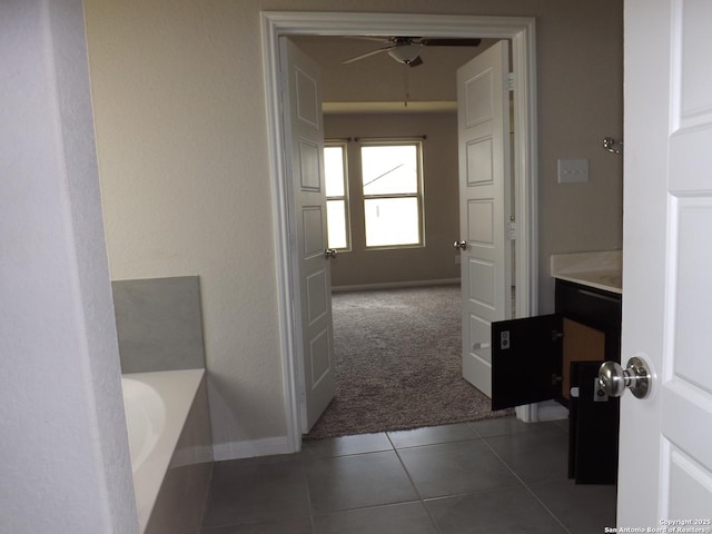 full bathroom with ceiling fan, baseboards, tile patterned flooring, and a bathtub