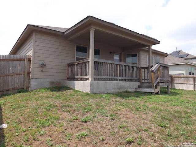 rear view of house featuring a lawn and a fenced backyard