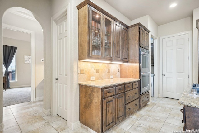 518 Ruidosa Downs, Helotes, TX 78023 - interior space with decorative backsplash, stainless steel double oven, arched walkways, baseboards, and recessed lighting