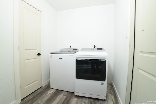 washroom with dark wood finished floors, baseboards, washer and dryer, and laundry area