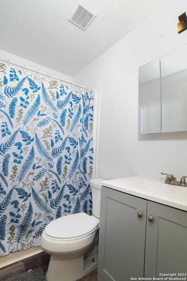 bathroom featuring wood finished floors, visible vents, toilet, vanity, and a shower with curtain