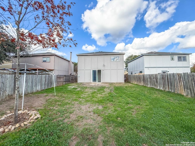 rear view of property featuring a yard and a fenced backyard