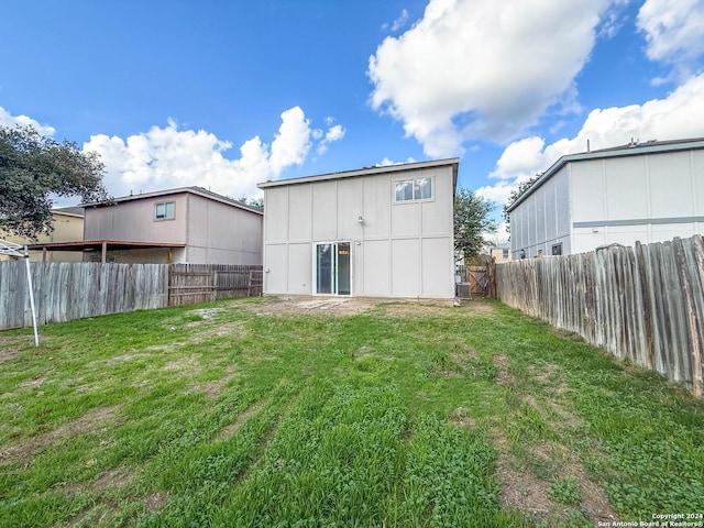back of property featuring a fenced backyard and a lawn