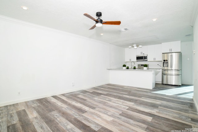 unfurnished living room with crown molding, wood finished floors, visible vents, and a ceiling fan
