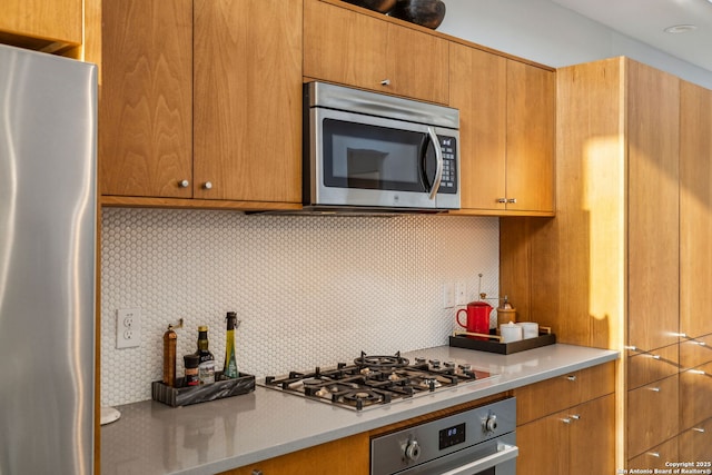 611 Simple Way, San Antonio, TX 78209 - kitchen featuring light countertops, brown cabinetry, appliances with stainless steel finishes, and decorative backsplash