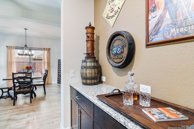 5112 Arrow Rdg, Schertz, TX 78154 - bar featuring decorative light fixtures, light wood-style floors, a notable chandelier, and baseboards