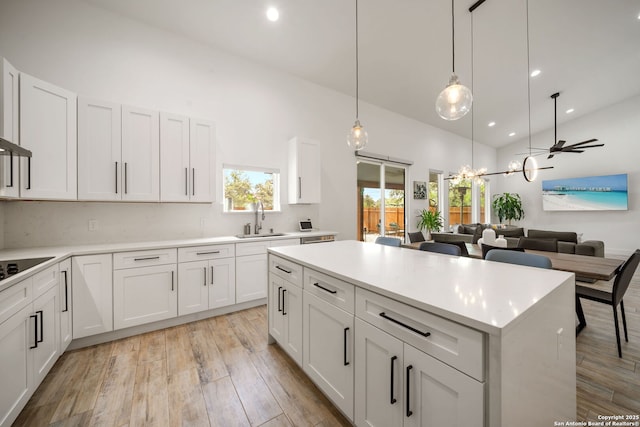 2114 Village, San Antonio, TX 78251 - kitchen with black electric cooktop, light countertops, a sink, light wood-style floors, and high vaulted ceiling