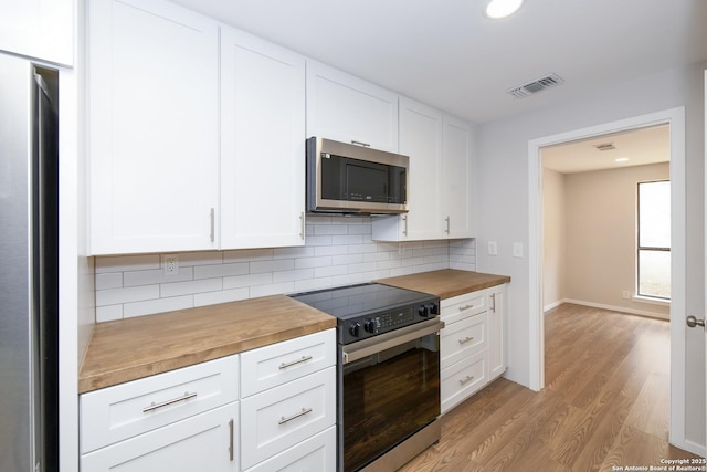kitchen featuring light wood-style flooring, wood counters, appliances with stainless steel finishes, white cabinets, and visible vents