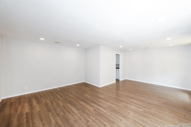 unfurnished room featuring wood finished floors, recessed lighting, visible vents, and baseboards