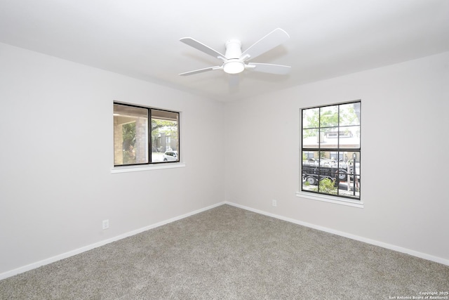 carpeted empty room with ceiling fan and baseboards