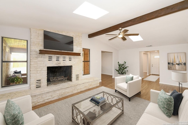 living room with a fireplace, lofted ceiling with skylight, a ceiling fan, baseboards, and wood finished floors