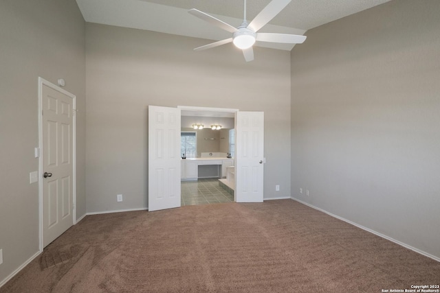 unfurnished bedroom with high vaulted ceiling, baseboards, ensuite bathroom, and carpet